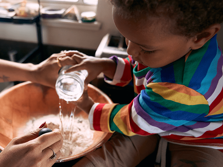 Toddler pouring water into a bowl