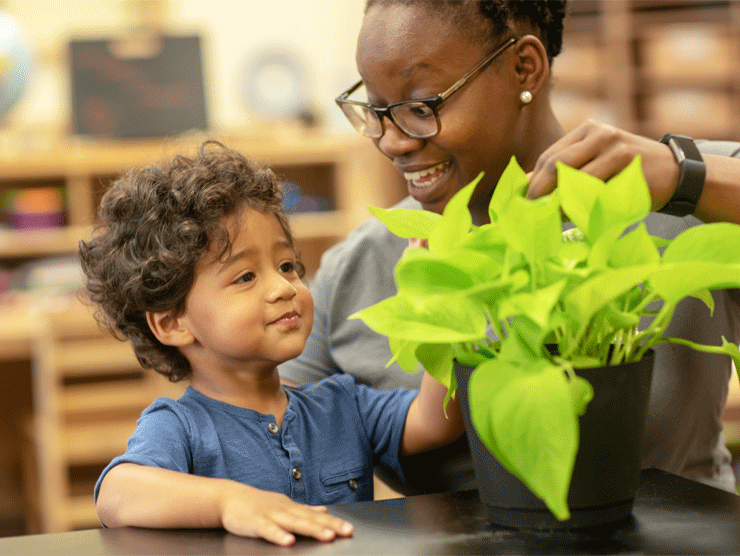 Preschooler and his child care teacher inspecting a plant
