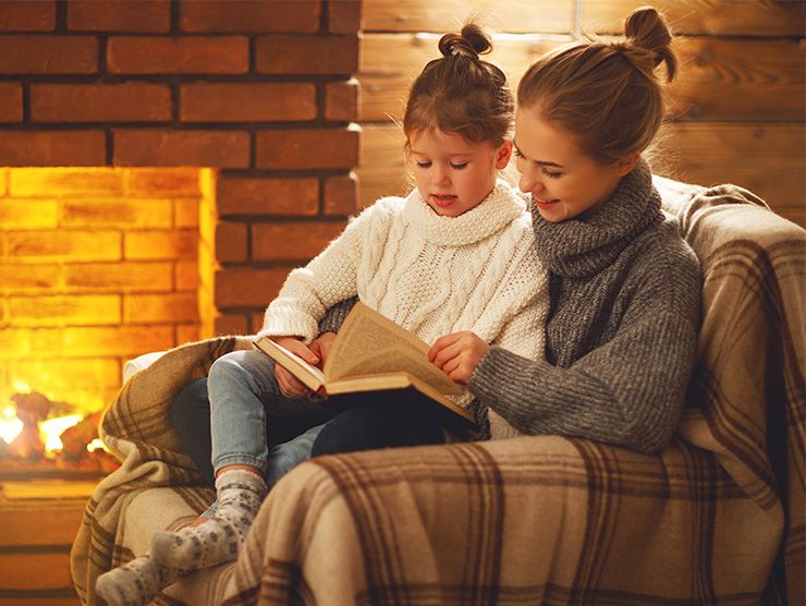 Mother and daughter reading by the fireplace