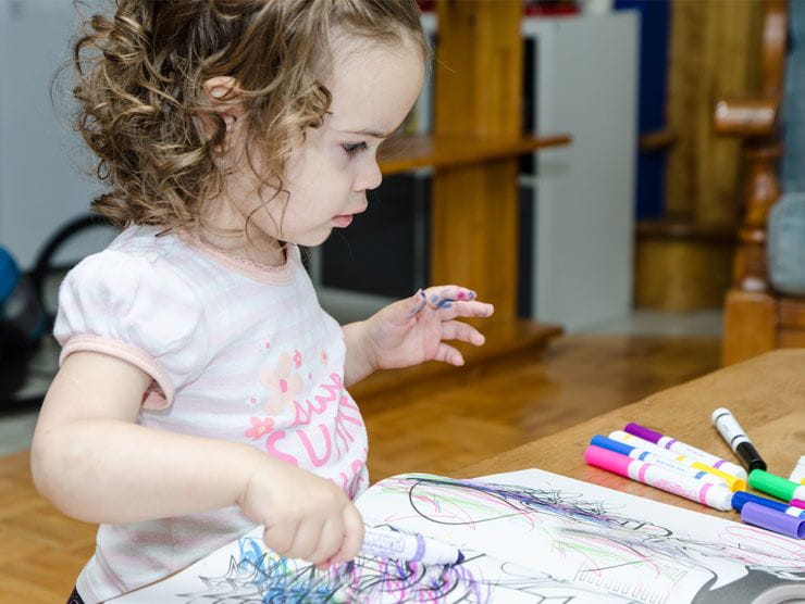 Young girl drawing in a coloring book