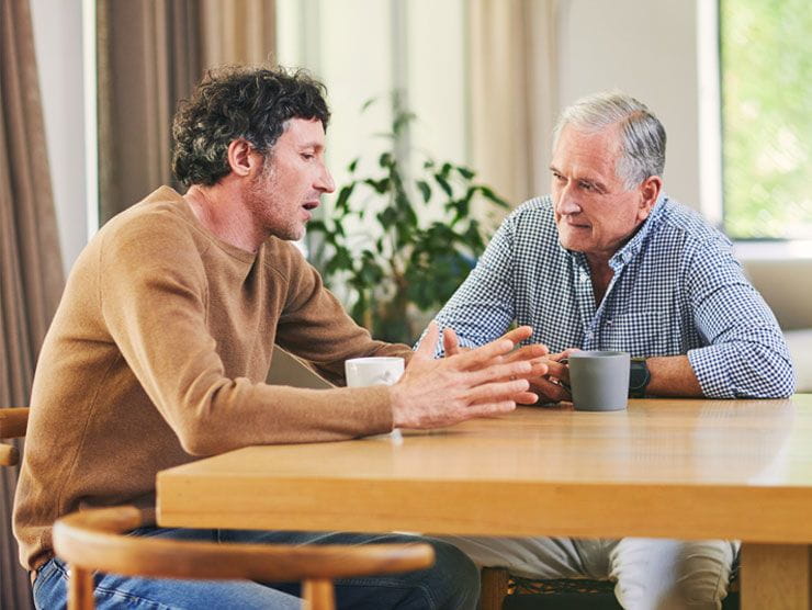 Father and son having a serious conversation at a table.