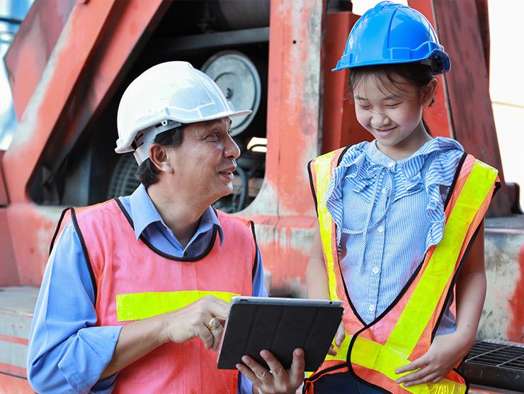 Dad and daughter in hardhats visiting a construction site. 